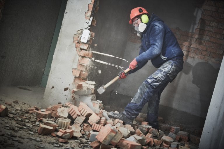 demolition work. Worker builder with sledgehammer destroying interior wall. Rearrangement during renovation. slow motion