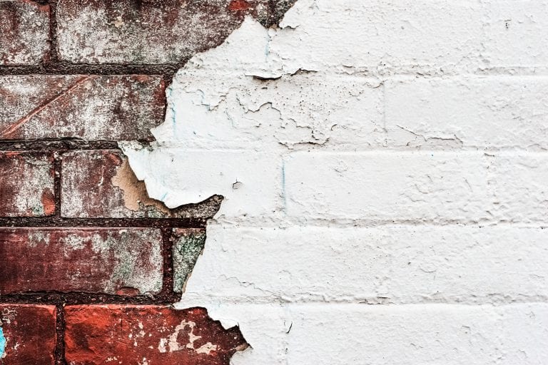 Texture of old peeling paint on a brick wall
