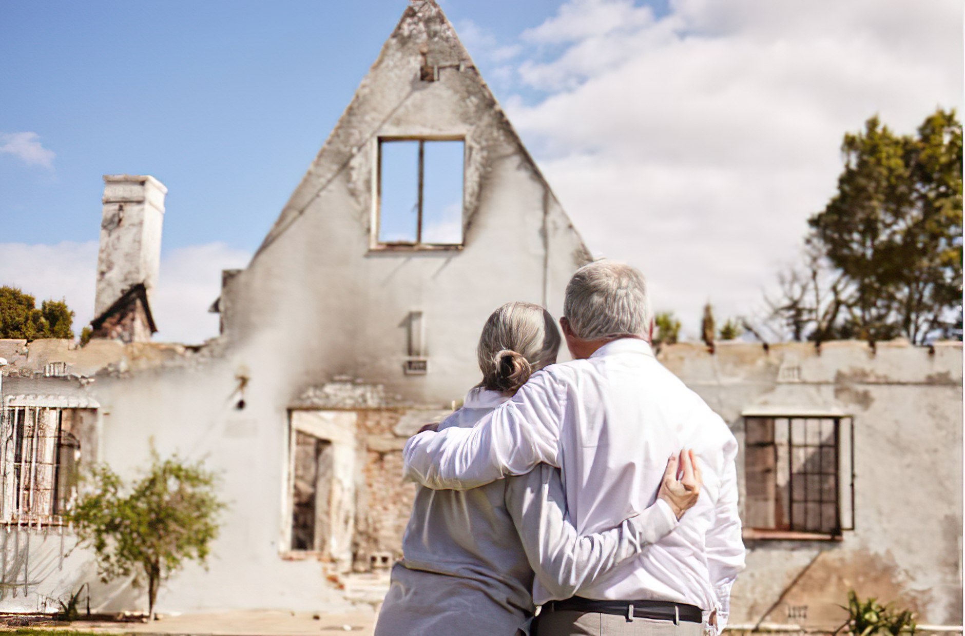 A severely fire-damaged house with smoke-stained walls and debris.