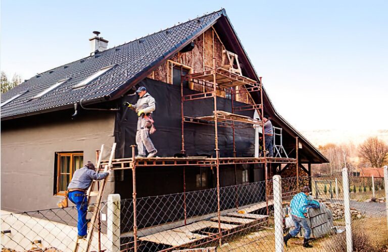 Restoration workers securing a fire-damaged property with boards and tarps