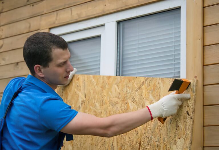 Technicians boarding up a fire-damaged window with plywood