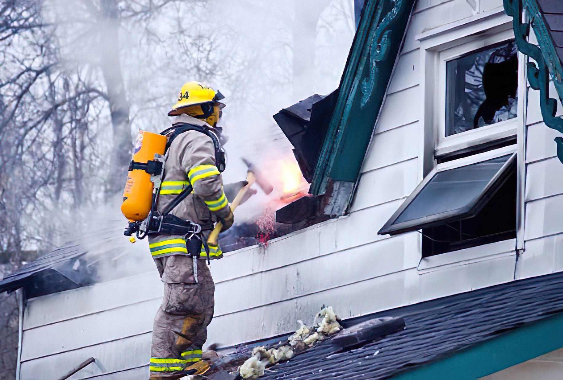 Firefighter at burned house with boarded-up window