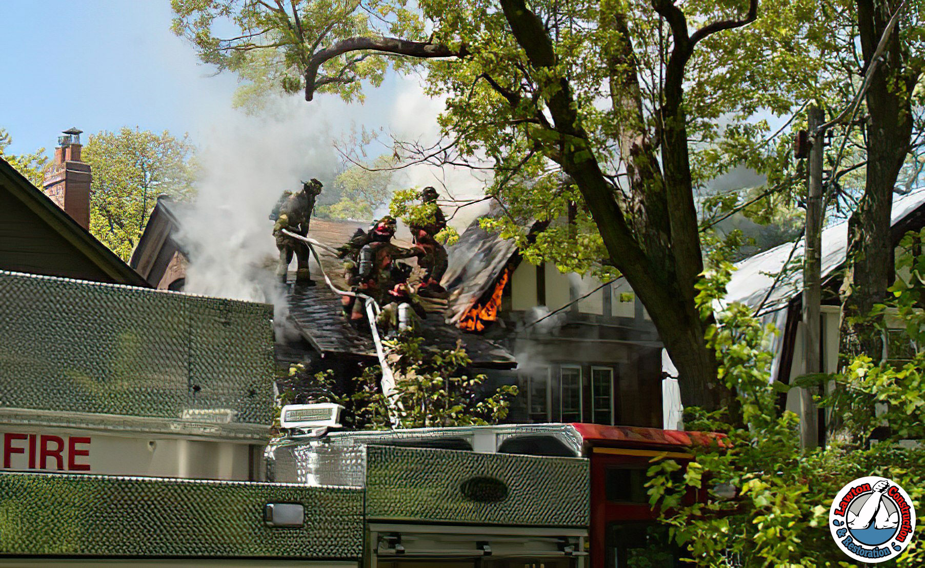 Fire-damaged house with smoke and flames visible
