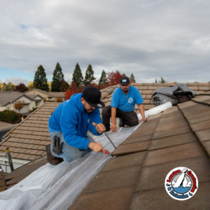 Aerial view of Los Angeles neighborhood with emergency blue roof tarps covering storm-damaged homes during February 2026 heavy rain and flooding